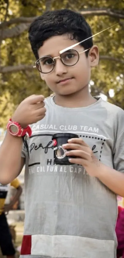 Young boy in glasses standing in an outdoor park.