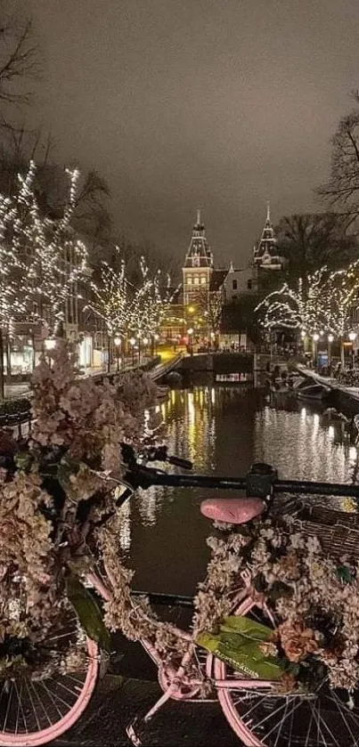 Flower-covered bicycle by a lit canal at night with enchanting city lights.