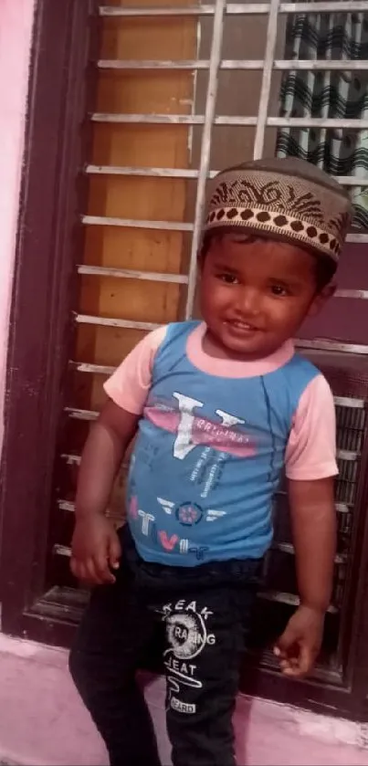 Smiling child in colorful clothes by a window.