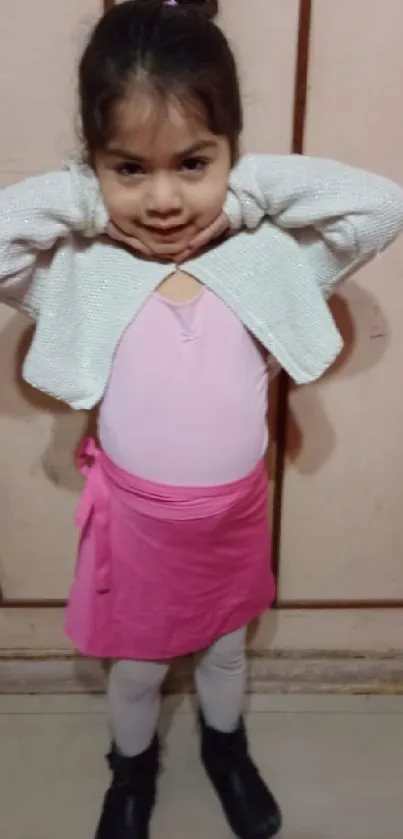 Young girl poses in pink skirt with white sweater.