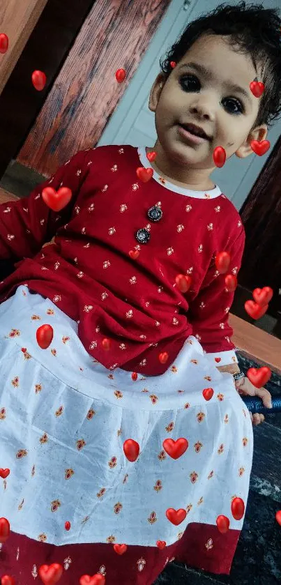 Adorable child in red dress sitting indoors.