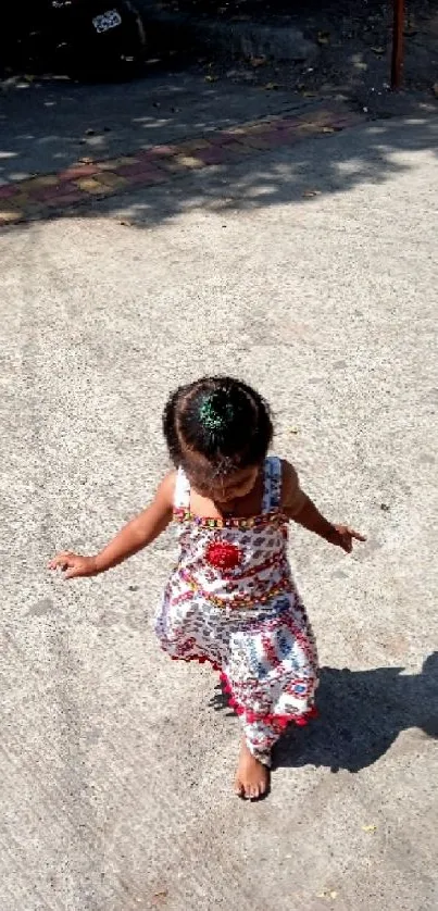 A child in colorful dress walking on a sunlit path.