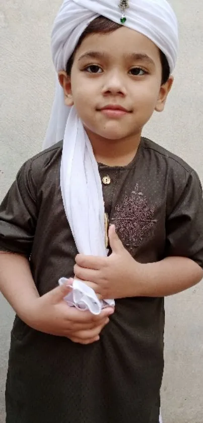 Young child in traditional brown attire with a white turban.