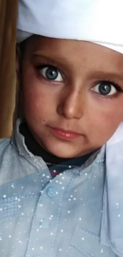 Child in traditional attire with bright blue eyes and serene expression.