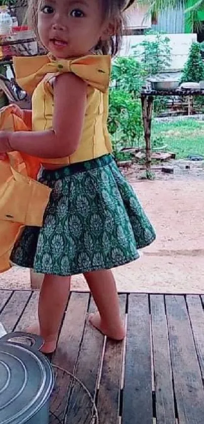 Child in a vibrant yellow and green outfit standing outdoors.