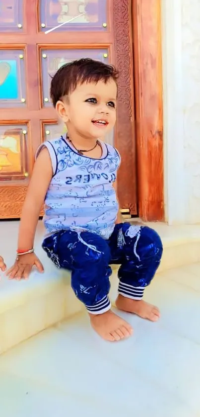 Happy child sitting by a carved wooden door.