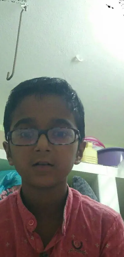 Portrait of a young boy with glasses in a casual room setting.