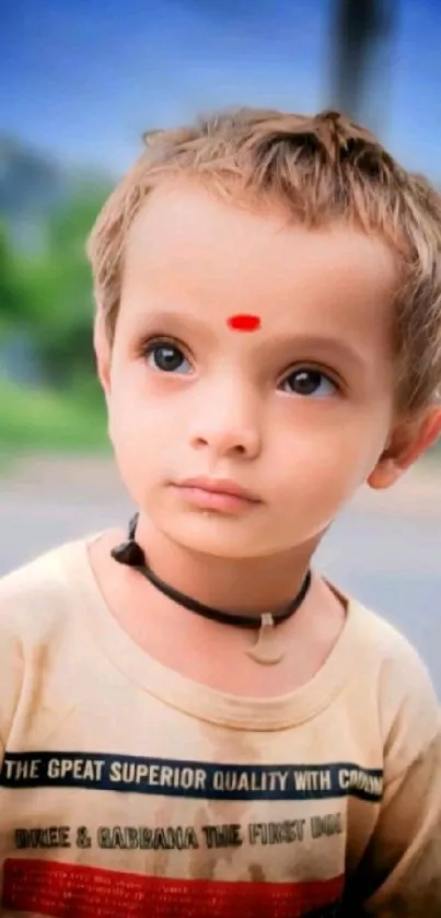 Adorable child with serene expression on a clear background, wearing a necklace and t-shirt.