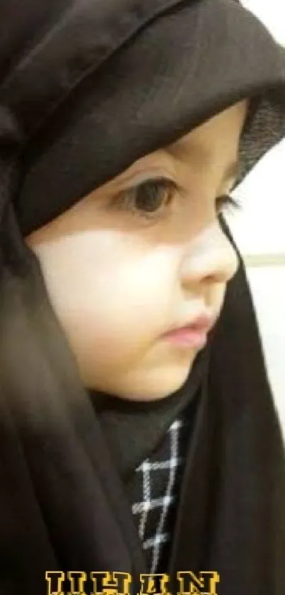 Portrait of a child in a black headscarf with serene expression.