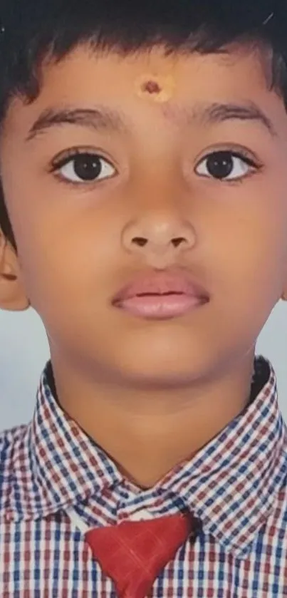 Portrait of a young boy in school uniform with expressive eyes and soft tones.