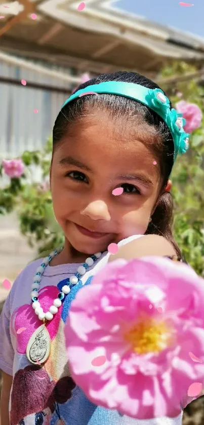 Smiling child with pink flowers, outdoors.