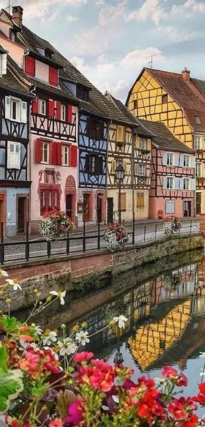 Vibrant village houses reflecting in canal with flowers.