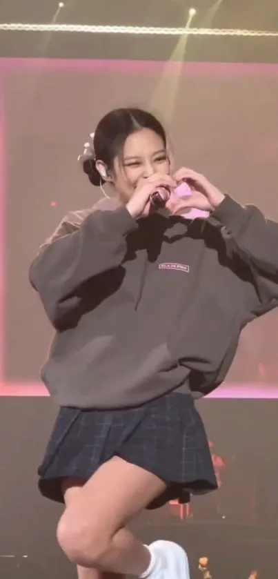 Energetic artist performing on stage with a heart gesture.