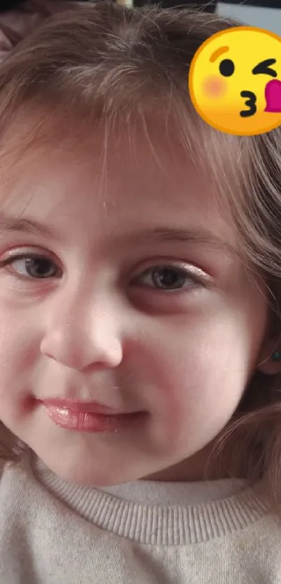 Child with cute emoji and brown hair smiling.