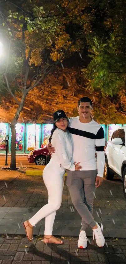 Couple posing under streetlights on a city street at night.