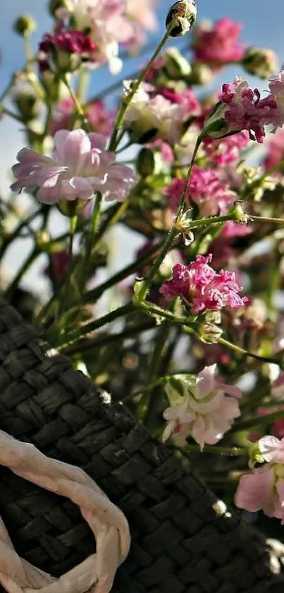 Woven basket with pink and white flowers under a blue sky.