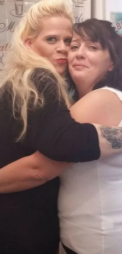 Two women share a warm embrace in a friendly and joyful moment.