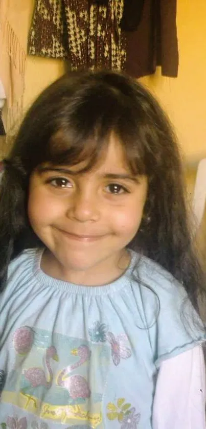 A young girl smiling warmly in a cozy room setting.