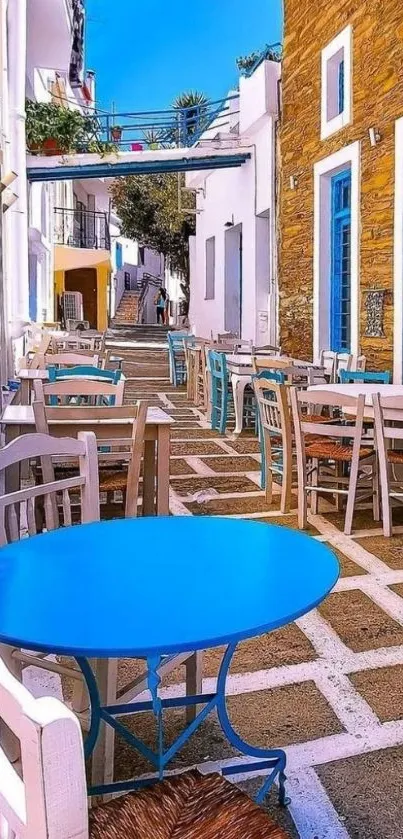 Greek alleyway with blue tables under a sunny sky.