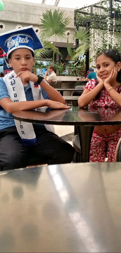 Two children indoors at a table with decor.