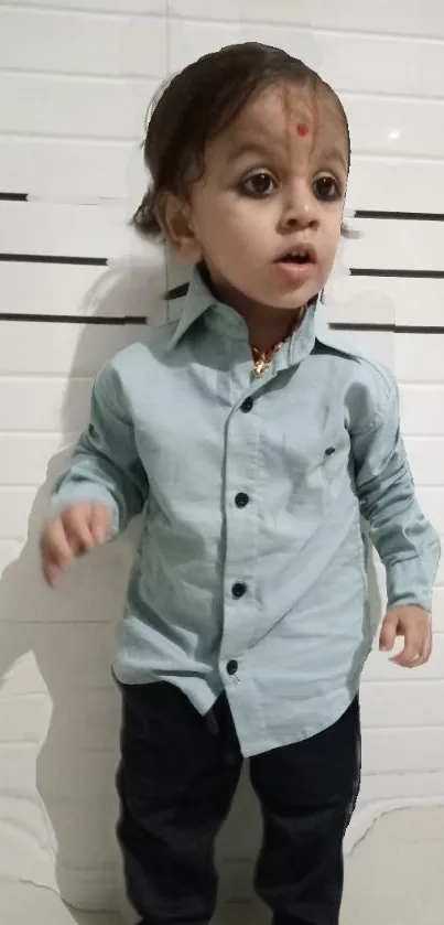 Child in light blue shirt against a simple white background.