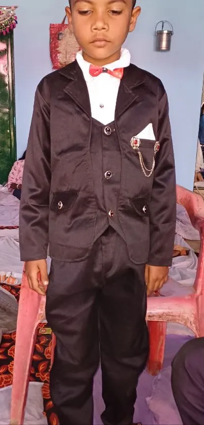 Young boy in a black suit standing elegantly.