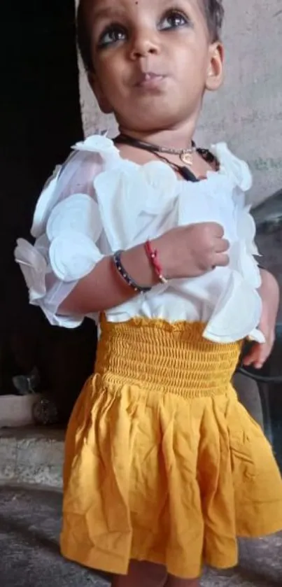 Adorable child in a yellow skirt posing indoors.