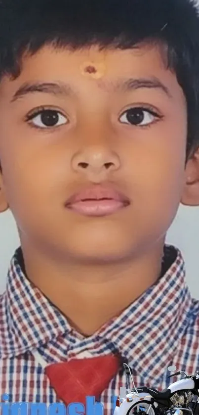 Portrait of young boy in checkered shirt with red tie on light background.