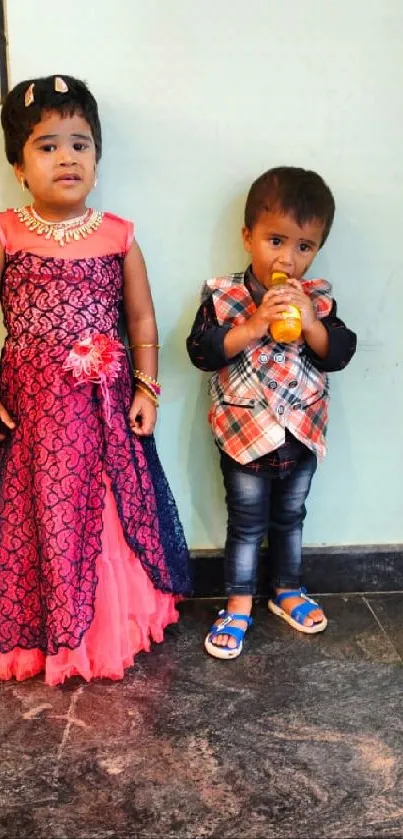 Two kids in traditional festive attire, standing joyfully.