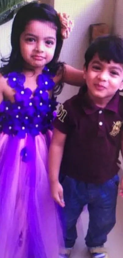 Two cute kids, one in purple dress, smiling happily.