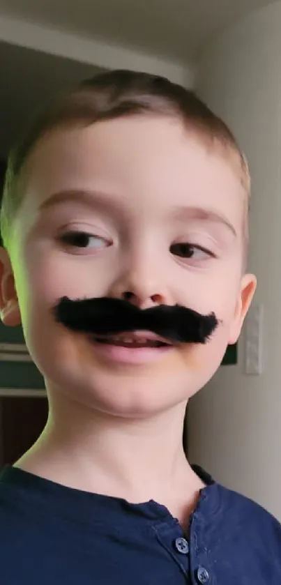 Adorable young boy with a fake moustache smiling in a cozy living room.