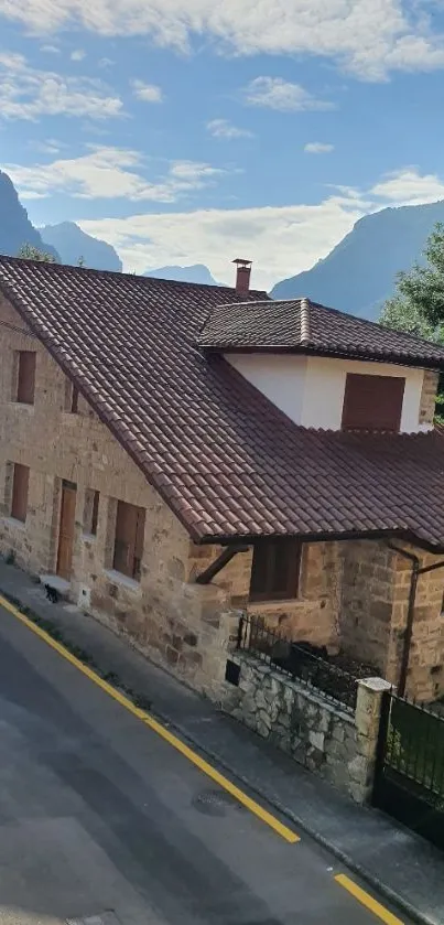 Charming stone house amidst mountain scenery with clear skies.