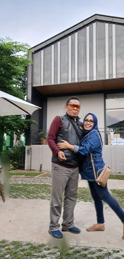 Couple posing outdoors in front of modern building.