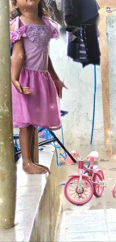 Girl in a pink dress standing beside a matching tricycle.