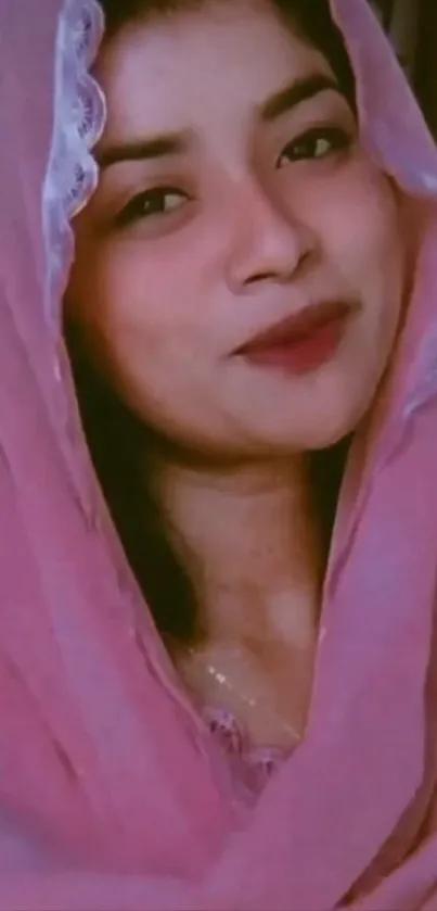 Portrait of a woman in a pink hijab, smiling gracefully.