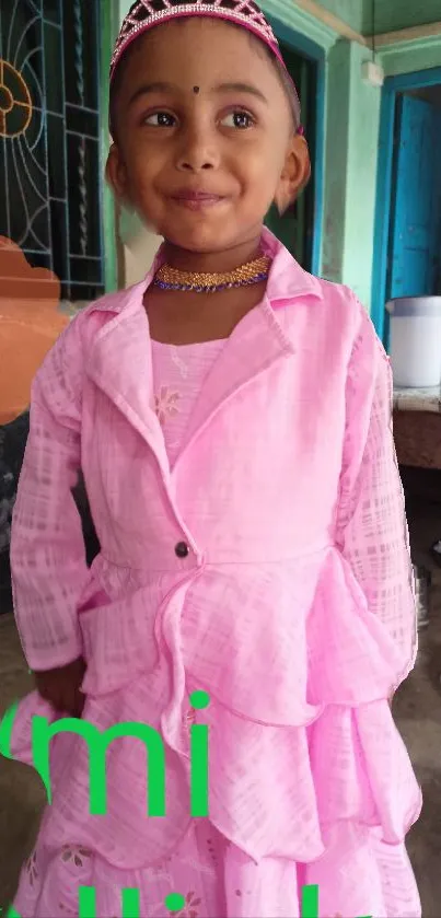 Adorable child wearing a pink dress smiling indoors.