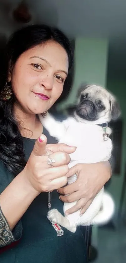 Woman holding a cute pug with a green background.