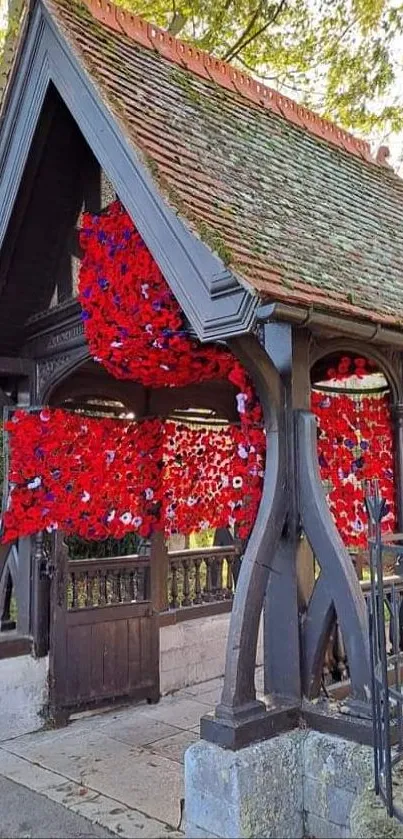 Rustic garden entrance adorned with red flowers under a canopy of trees.