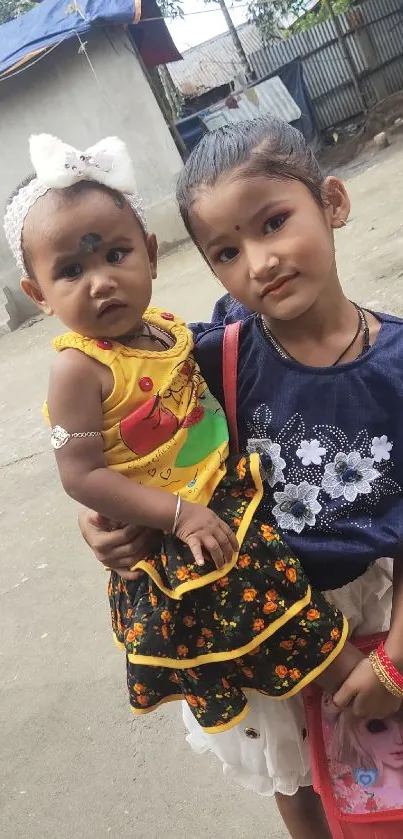 Two young siblings smiling in colorful traditional attire.