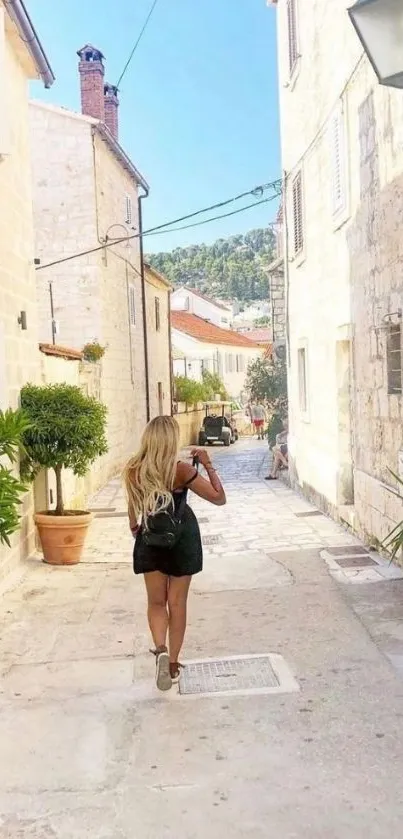 Woman walking on a charming sunny street with stone buildings.