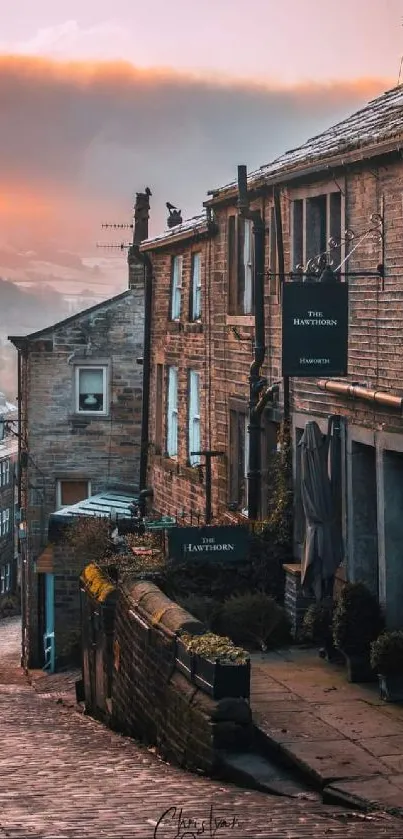 Cobbled village street at sunset with warm glowing sky.