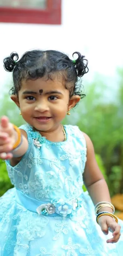 Adorable toddler in sky blue dress reaching out with a smile in a lush garden.