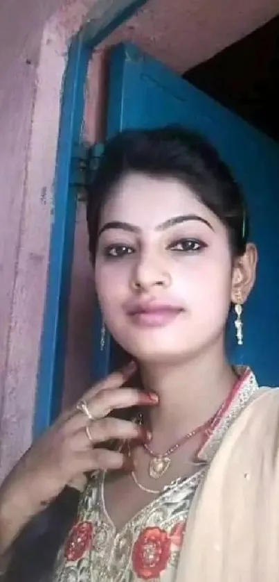 Portrait of a woman in traditional attire, set against a rustic blue doorway backdrop.