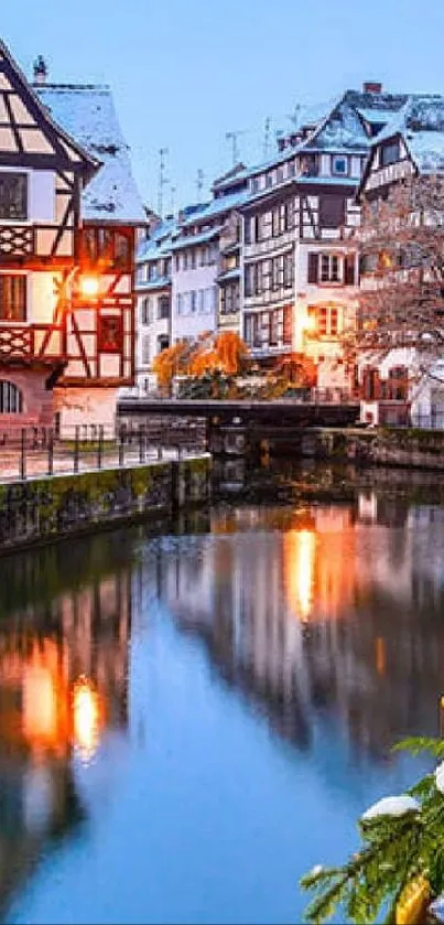 Charming winter river scene with snow-dusted rooftops and a calm reflection in the water.