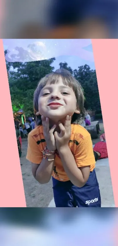 Smiling child posing playfully in a pink-themed wallpaper.