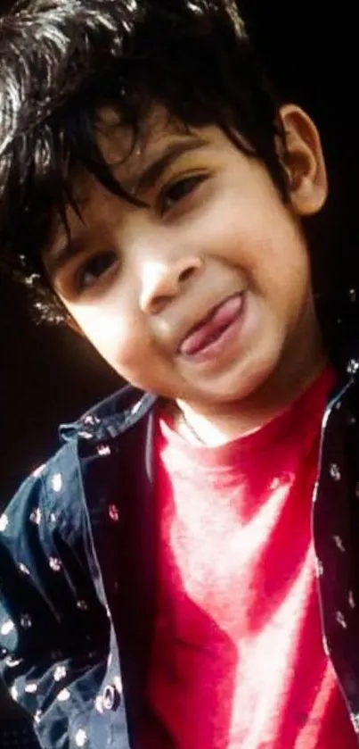 Cheerful child wearing a red shirt smiling at the camera.