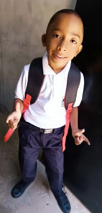 Cheerful schoolboy in uniform with a backpack, smiling confidently.