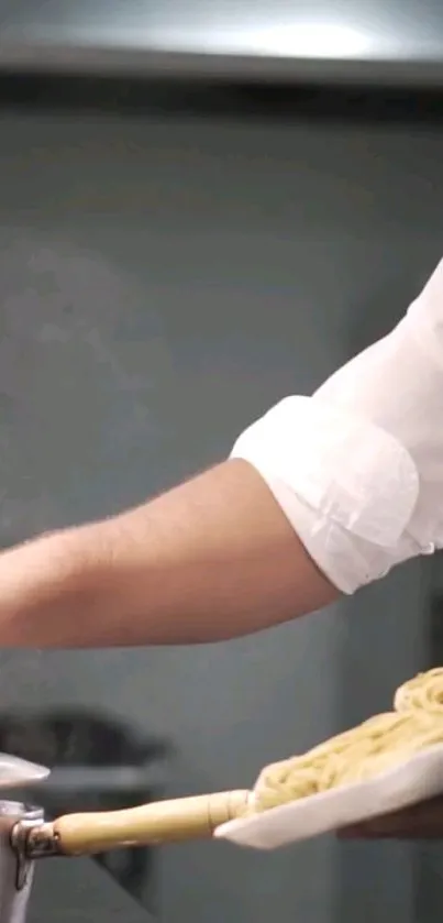 Chef's hands preparing a pasta dish in a professional kitchen setting.