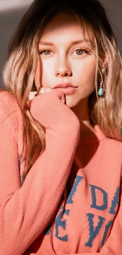 Young woman in coral pink sweater with long hair and casual style.