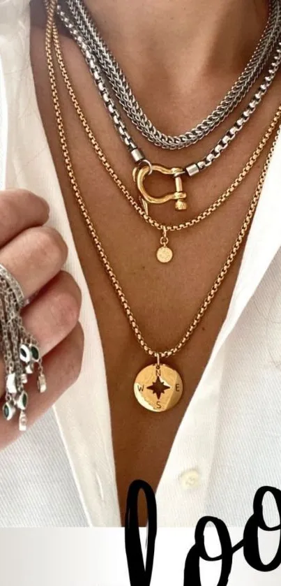 Layered gold and silver necklaces on a white shirt for chic fashion style.